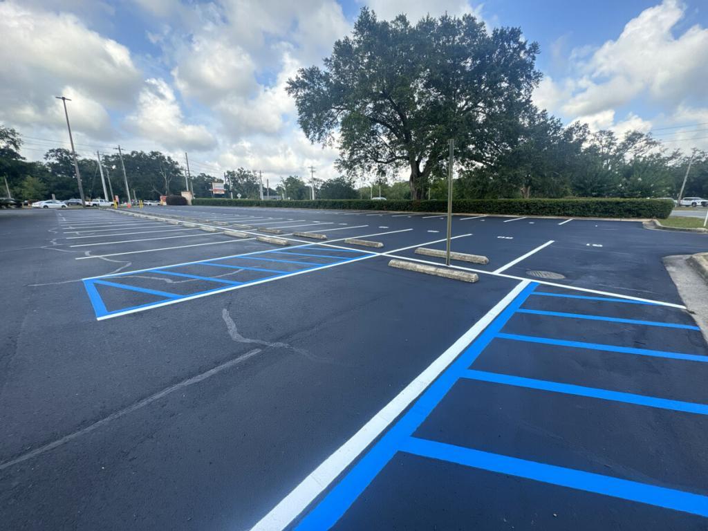 Crew repainting parking lot lines and applying fresh sealcoat using striping equipment
