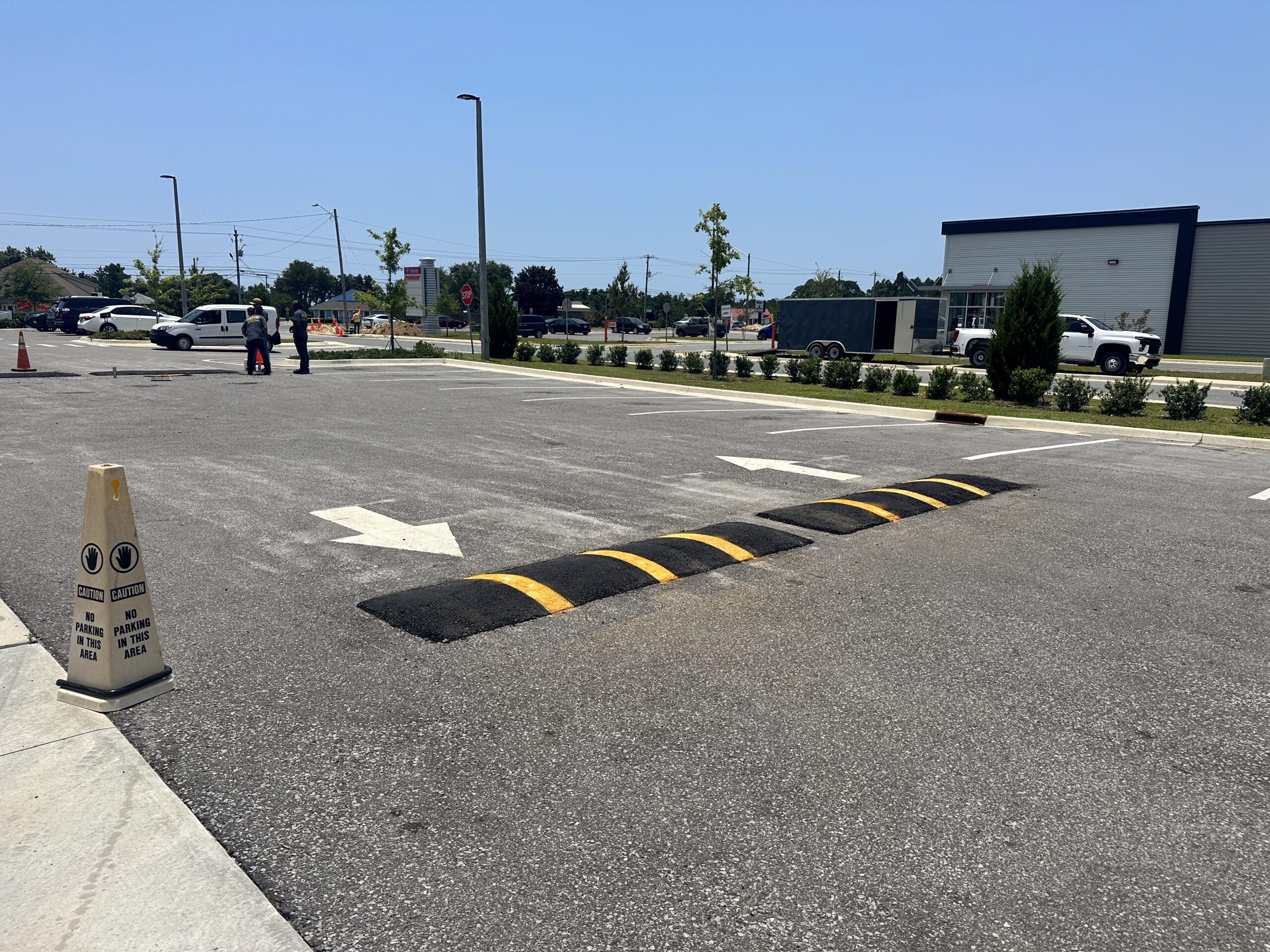 Raised asphalt speed bump with yellow warning bands and a nearby white directional arrow