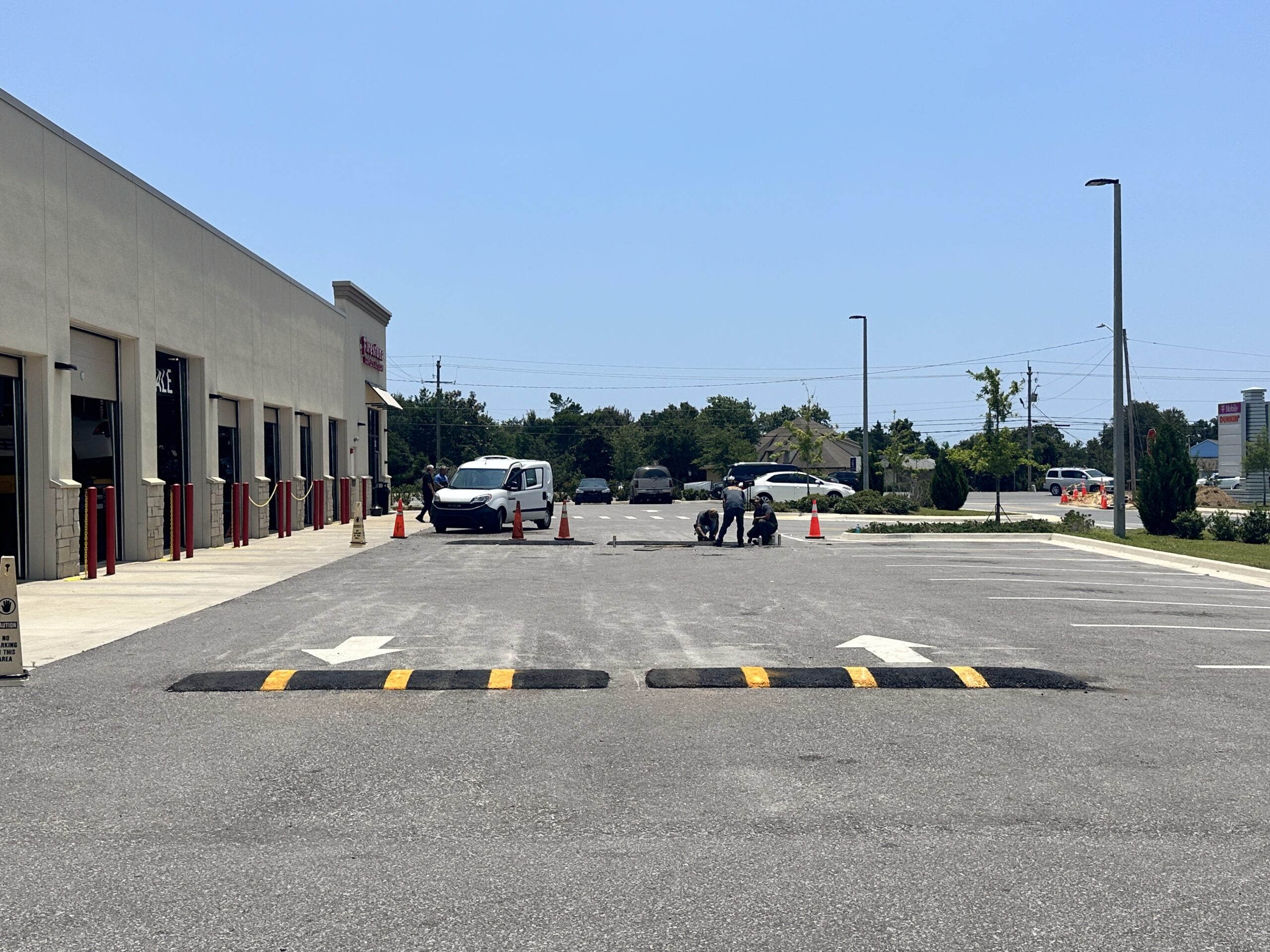 Raised speed bumps with yellow warning bands across a commercial driveway