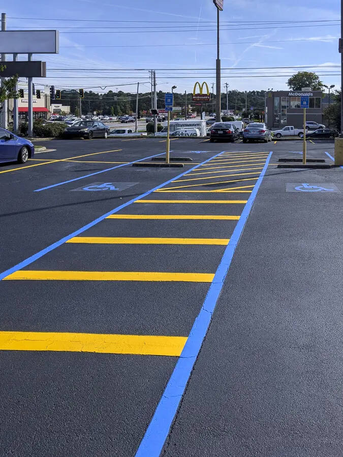 Freshly striped commercial parking lot with bright white and yellow lines and handicap symbol by CasTech Products